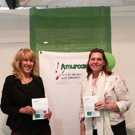 Dos miembros de AMURCAE en una mesa informativa de la Semana de la Salud de Molina de Segura, con el cartel de la asociación